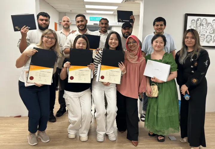 A happy group of ELS students holding their ELS certificates and posing for a photograph with their teachers during graduation day